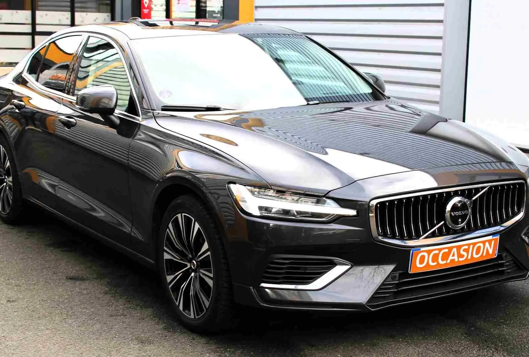 Volvo S60 hybride rechargeable gris métal vue 3/4 avant droit avec calandre chromée et plaque "OCCASION".