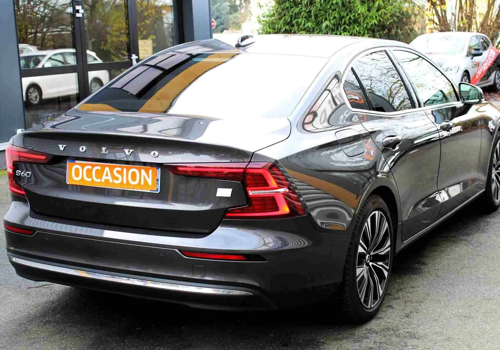 Vue 3/4 arrière droite d'une Volvo S60 hybride rechargeable gris métal avec jantes alliage et badge S60 visible.