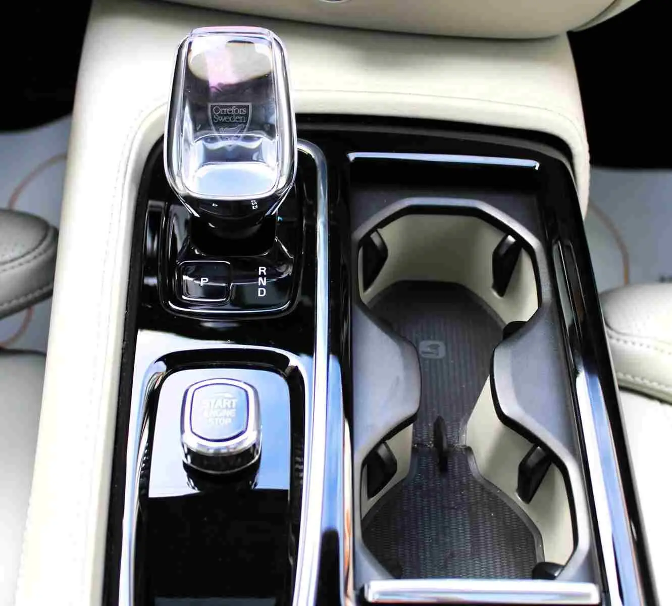 Gros plan sur la console centrale beige du Volvo S60 2024 avec levier de vitesses cristal et bouton start/stop.