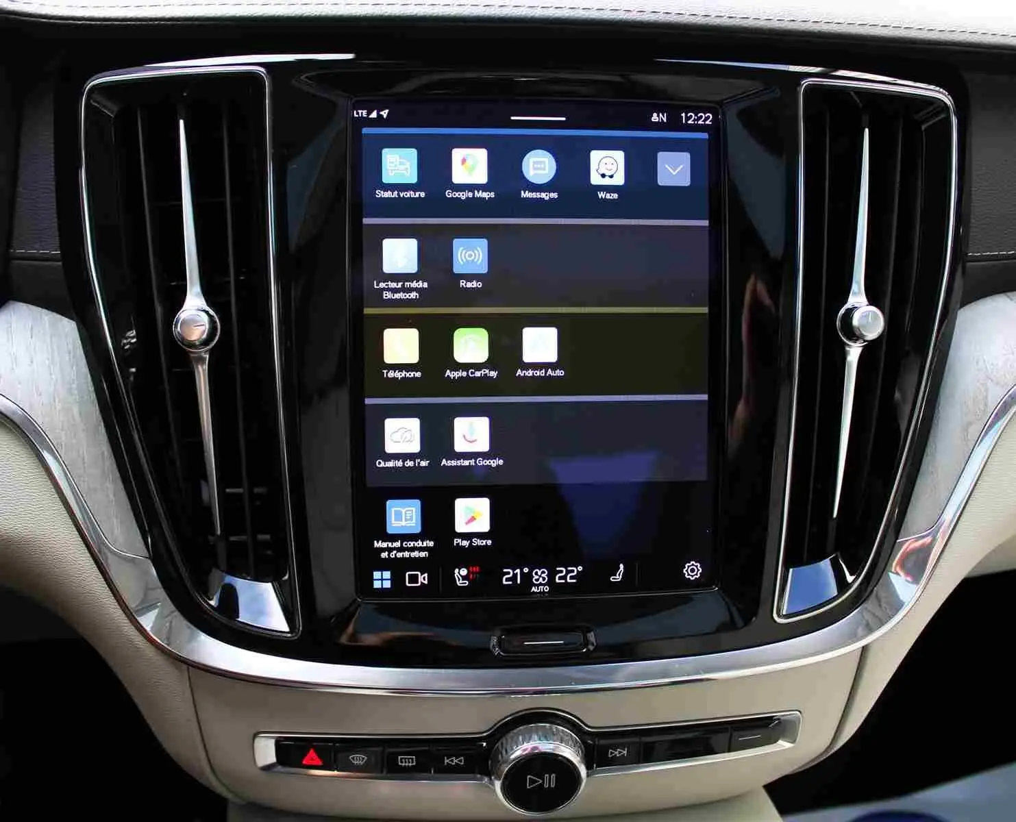 Écran tactile central avec interface multimédia, entouré de grilles d'aération chromées dans l'habitacle beige d'une Volvo S60 2024.