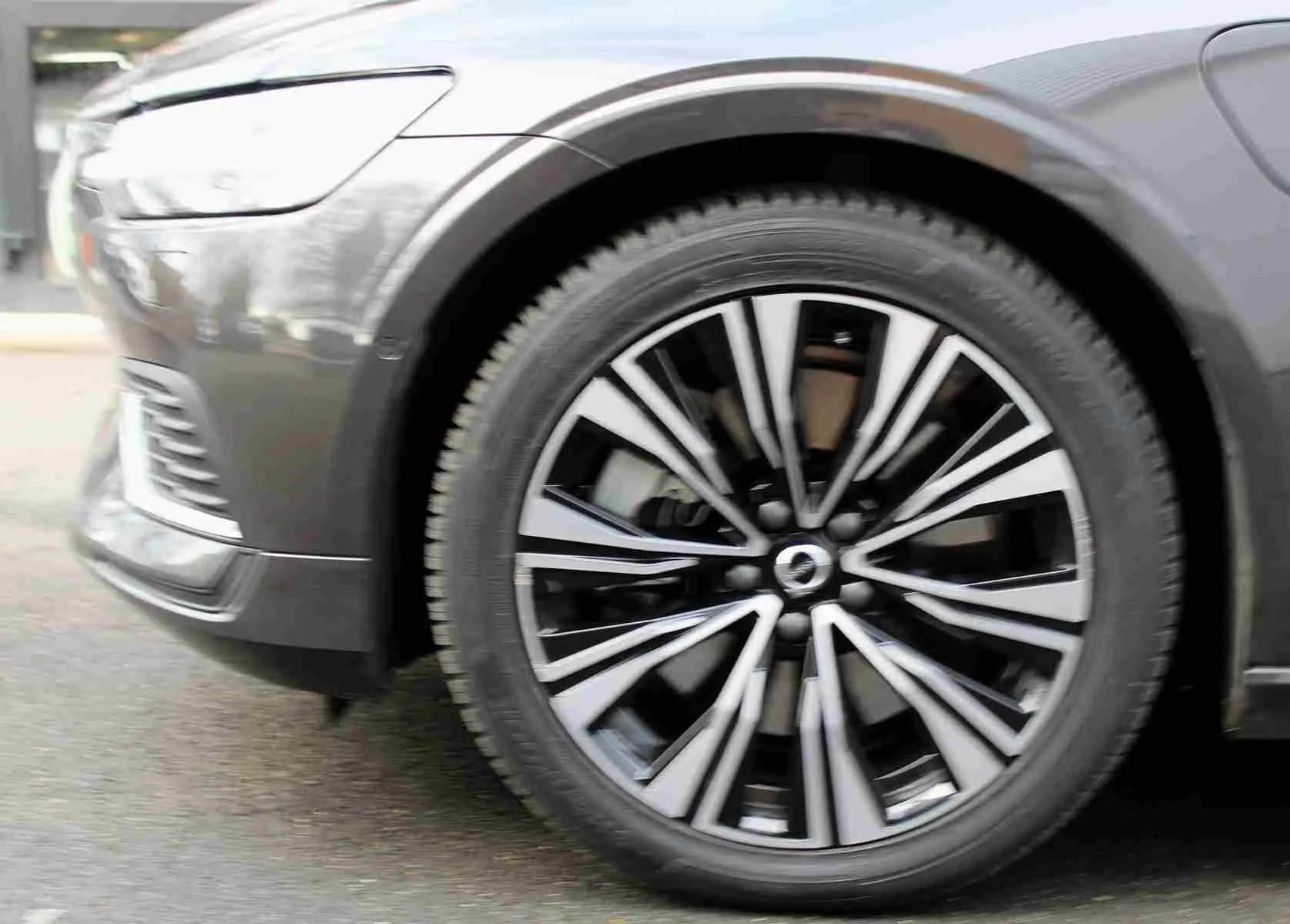 Gros plan sur la roue avant gauche d'une Volvo S60 gris métal 2024, mettant en valeur la jante au design moderne bicolore.