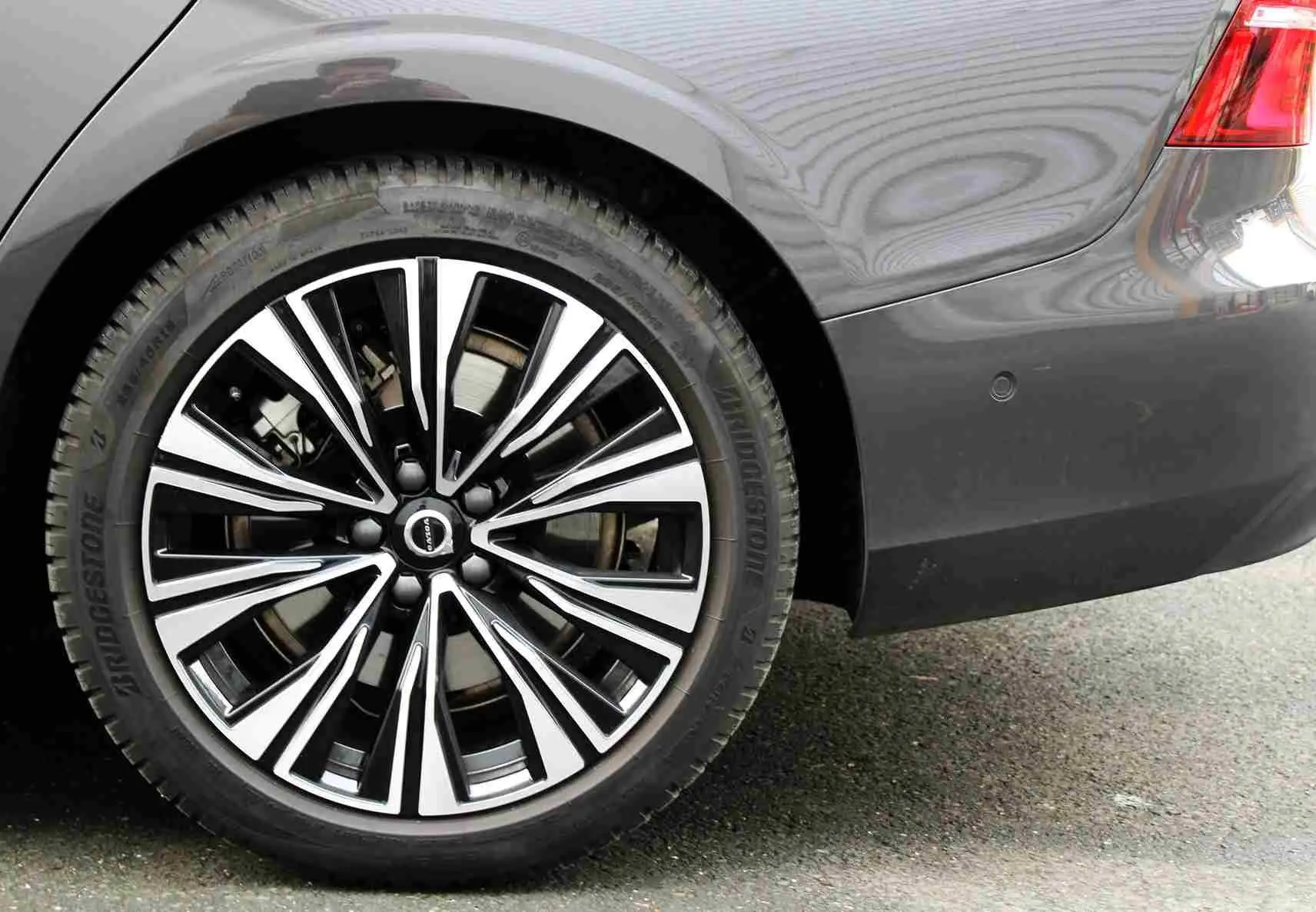 Gros plan sur la roue arrière droite et le pare-chocs gris métal d'une Volvo S60 T6 hybride rechargeable 2024.