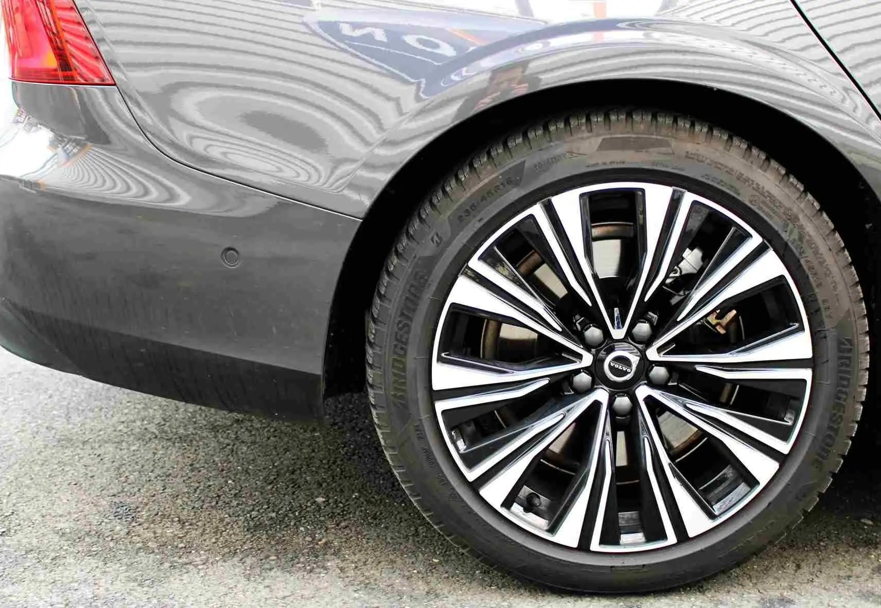Gros plan sur la roue arrière droite d'une Volvo S60 gris métal 2024, mettant en valeur la jante alliage au design moderne.