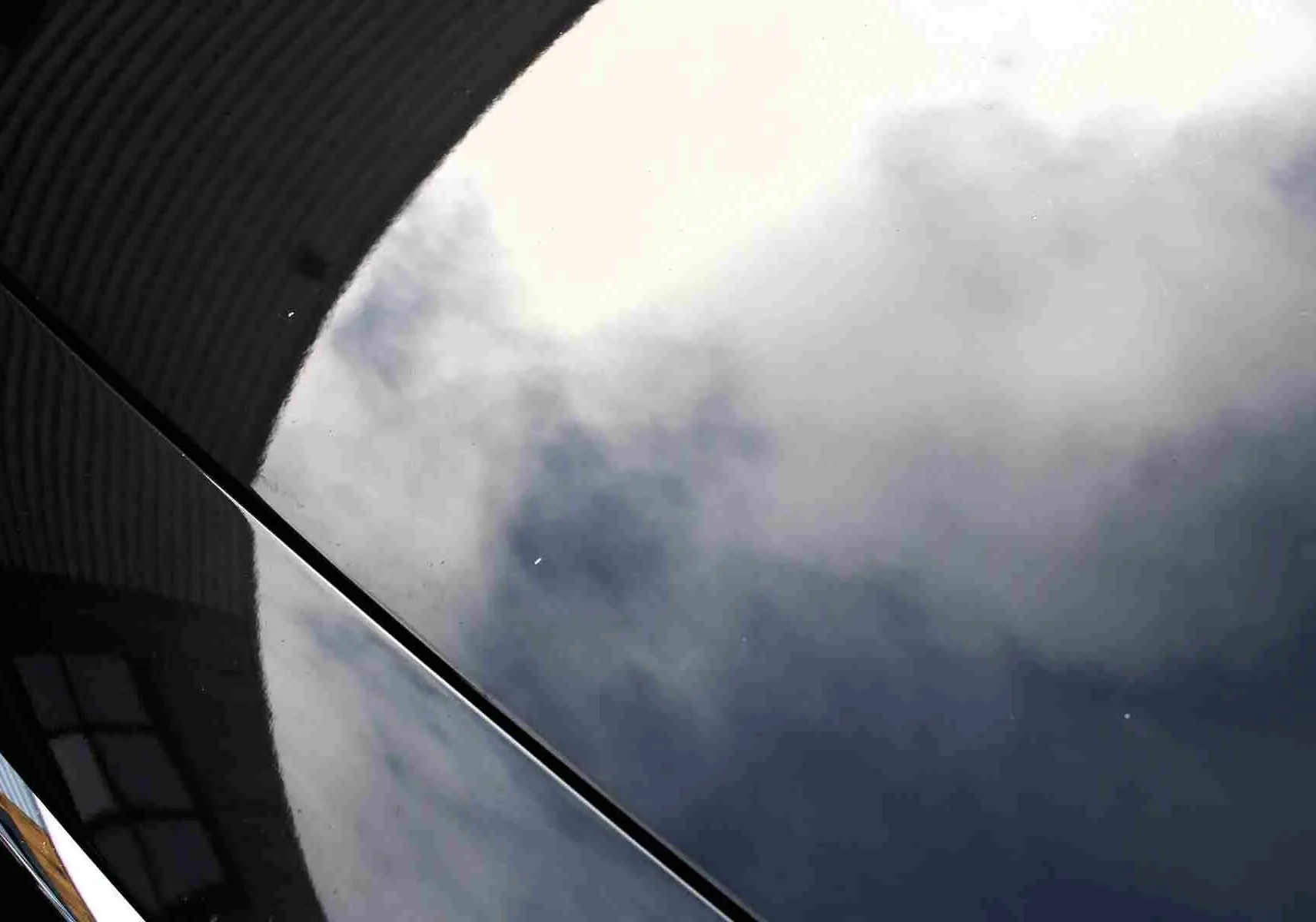 Reflet nuageux sur la carrosserie gris métal d'une Volvo S60 T6 AWD 2024 vue en gros plan côté droit.