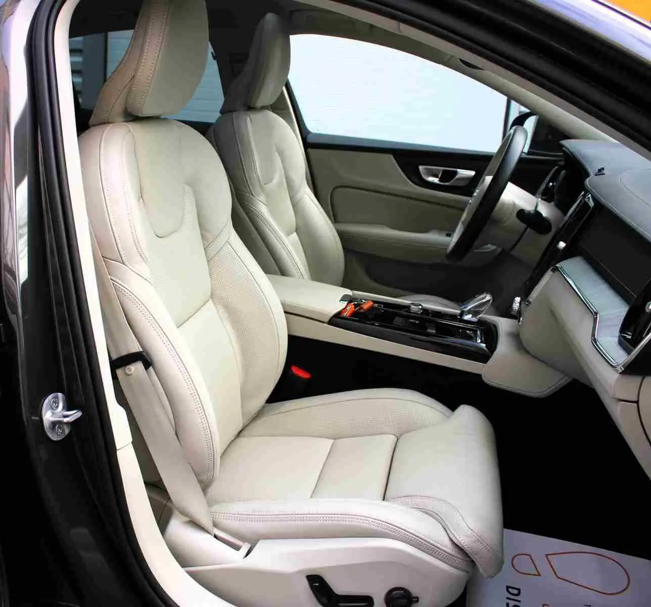 Intérieur clair du Volvo S60 T6 AWD 2024 vu côté conducteur, sièges cuir beige et console centrale moderne.