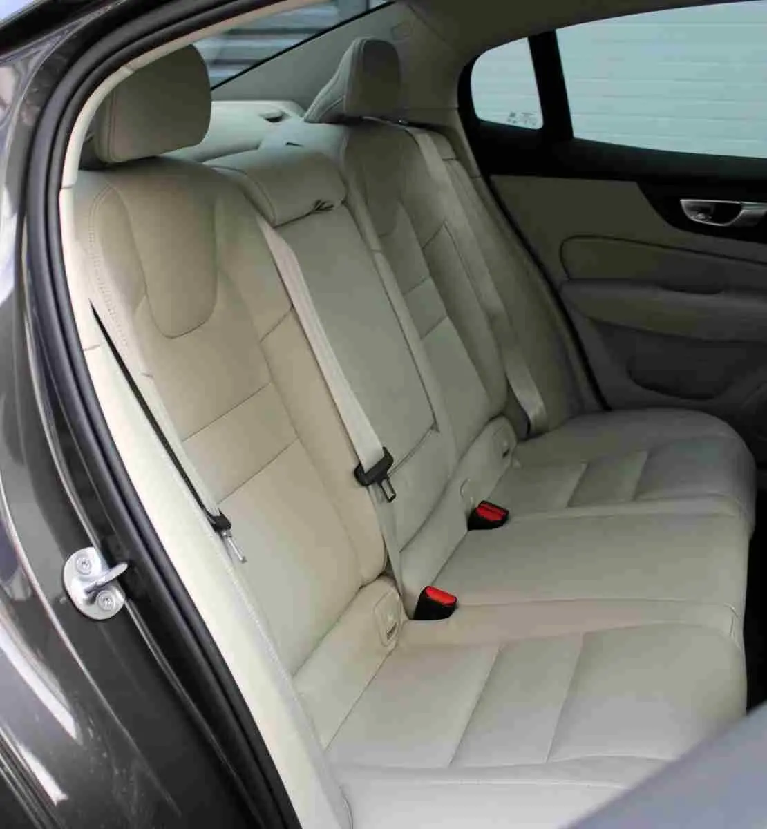 Vue côté gauche des sièges arrière en cuir beige clair d'une Volvo S60 gris métal 2024, détails intérieurs visibles.