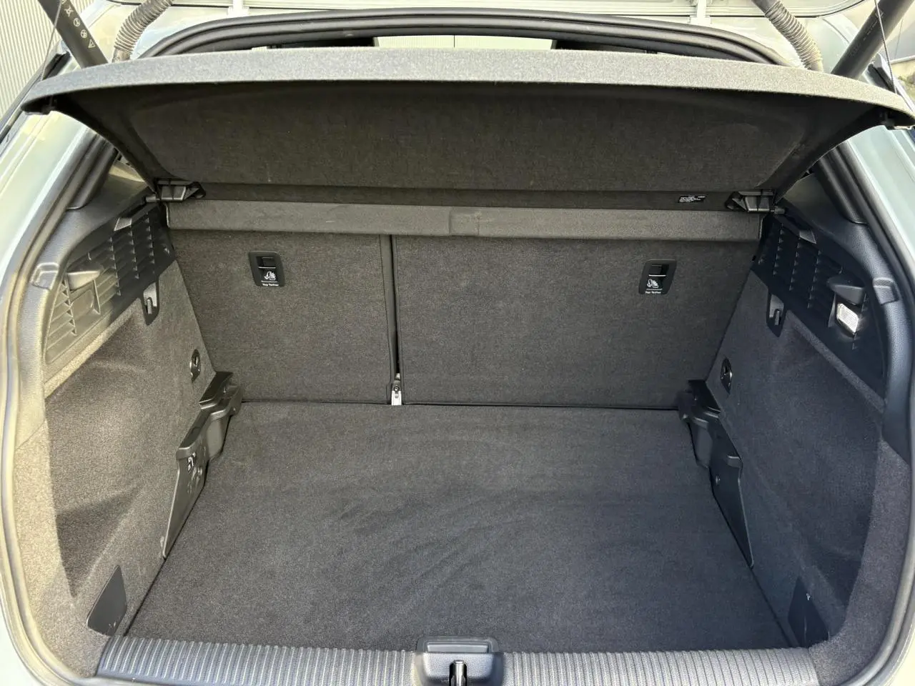 Coffre ouvert vu de l'arrière d'un Audi Q2 35 TDI S-Line 2025, intérieur tissu noir spacieux et propre.