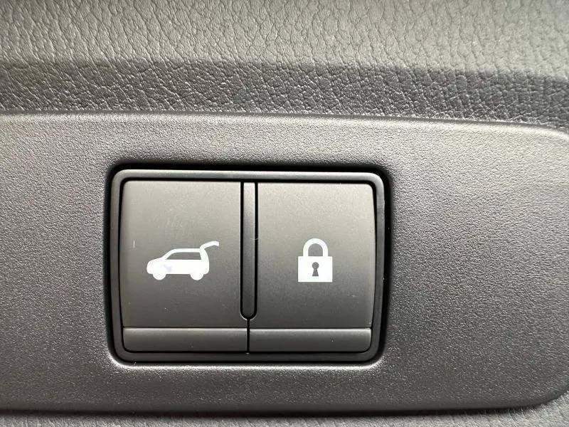 Boutons intérieurs de commande du coffre et de verrouillage, sur panneau noir texturé d’un Nissan Qashqai Hybrid e-POWER blanc nacré 2025.