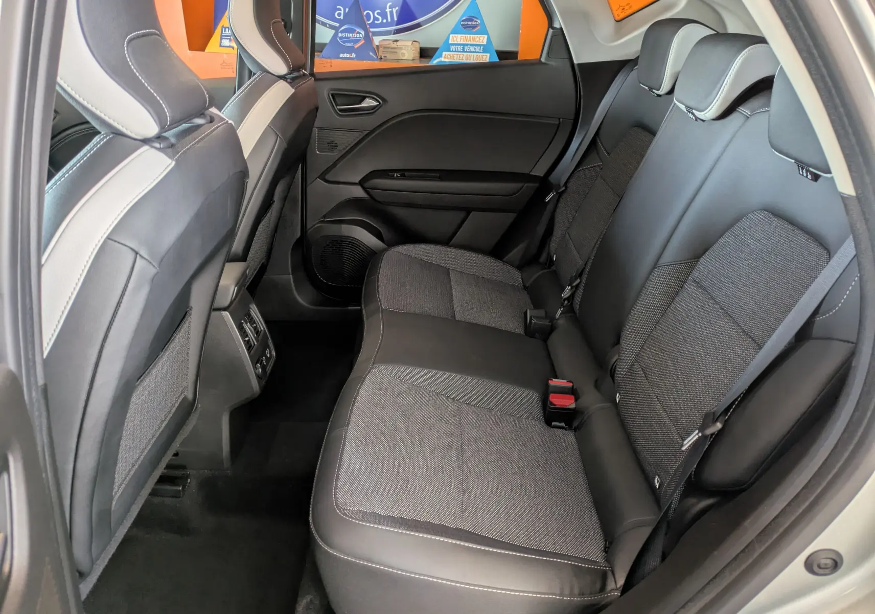 Vue intérieure arrière côté droit du Renault Captur II Techno 2023, sièges tissu et cuir noir avec surpiqûres blanches.