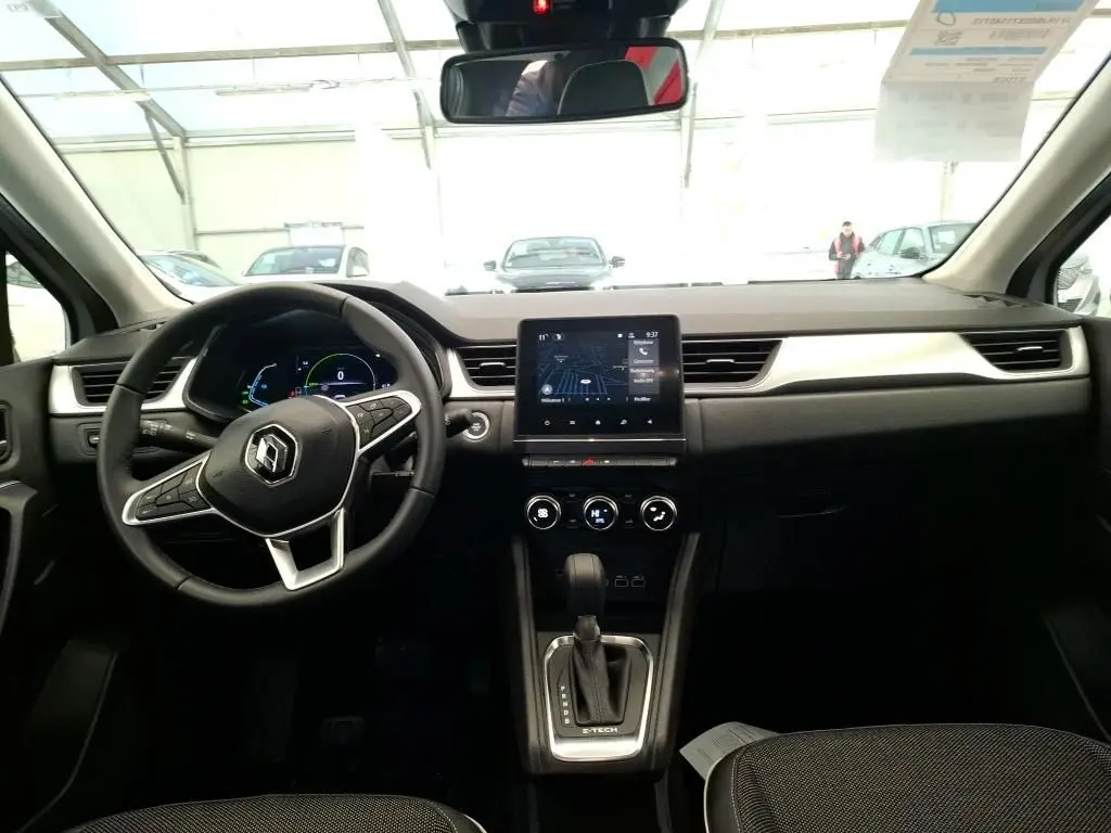 Vue 3/4 arrière droite d'un Renault Captur II gris Highland avec jantes alliage et vitres teintées en intérieur showroom.