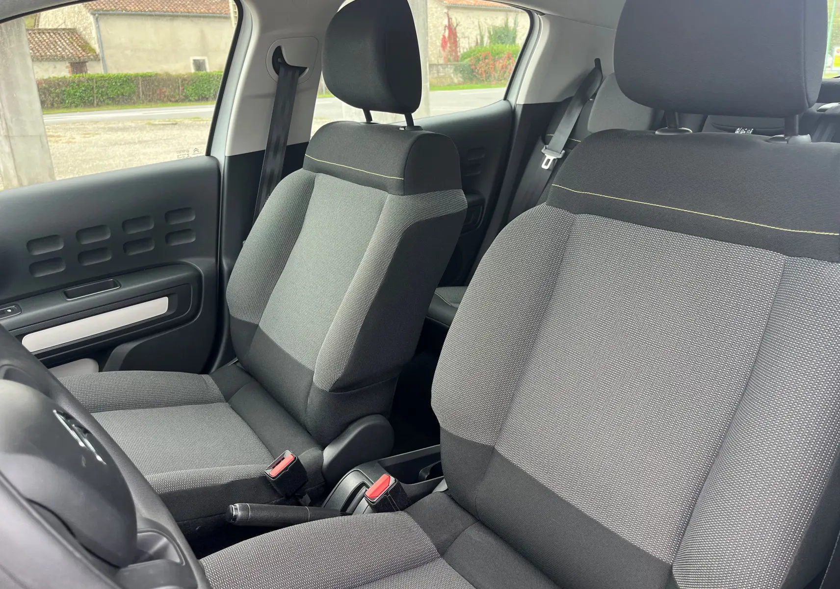 Vue intérieure des sièges avant gris et noir en tissu de la Citroën C3 2017, version 1.2 THP 68 LIVE blanche.