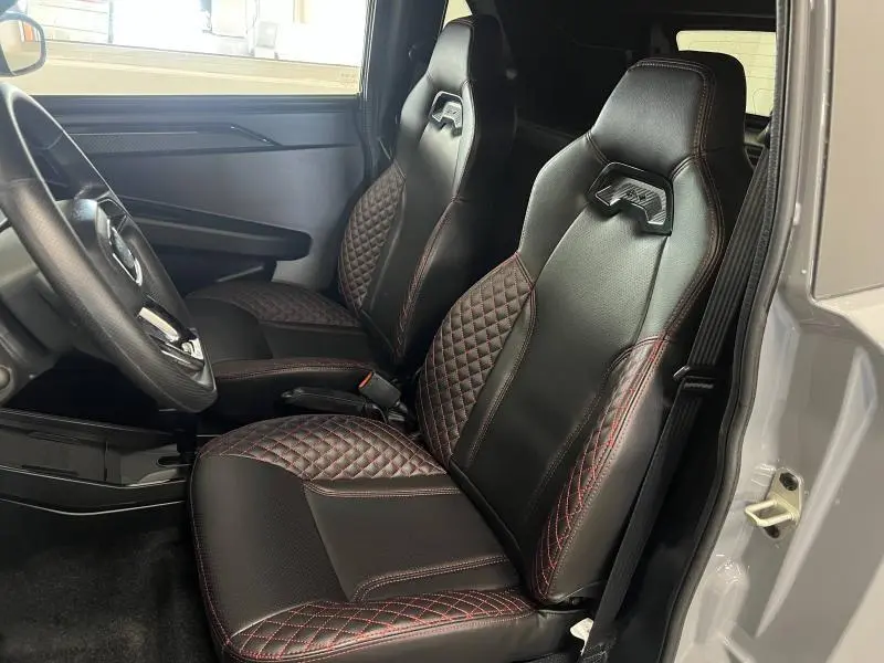 Vue intérieure côté gauche de la LIGIER JS50 SPORT ULTIMATE E5+ 2025, sièges noirs avec surpiqûres rouges et volant visible.