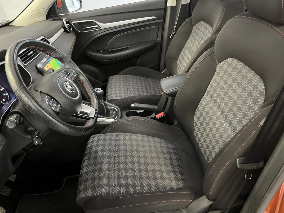 Intérieur avant droit du MG ZS 2022, sièges tissu à motif pied-de-poule et volant cuir avec surpiqûres rouges.