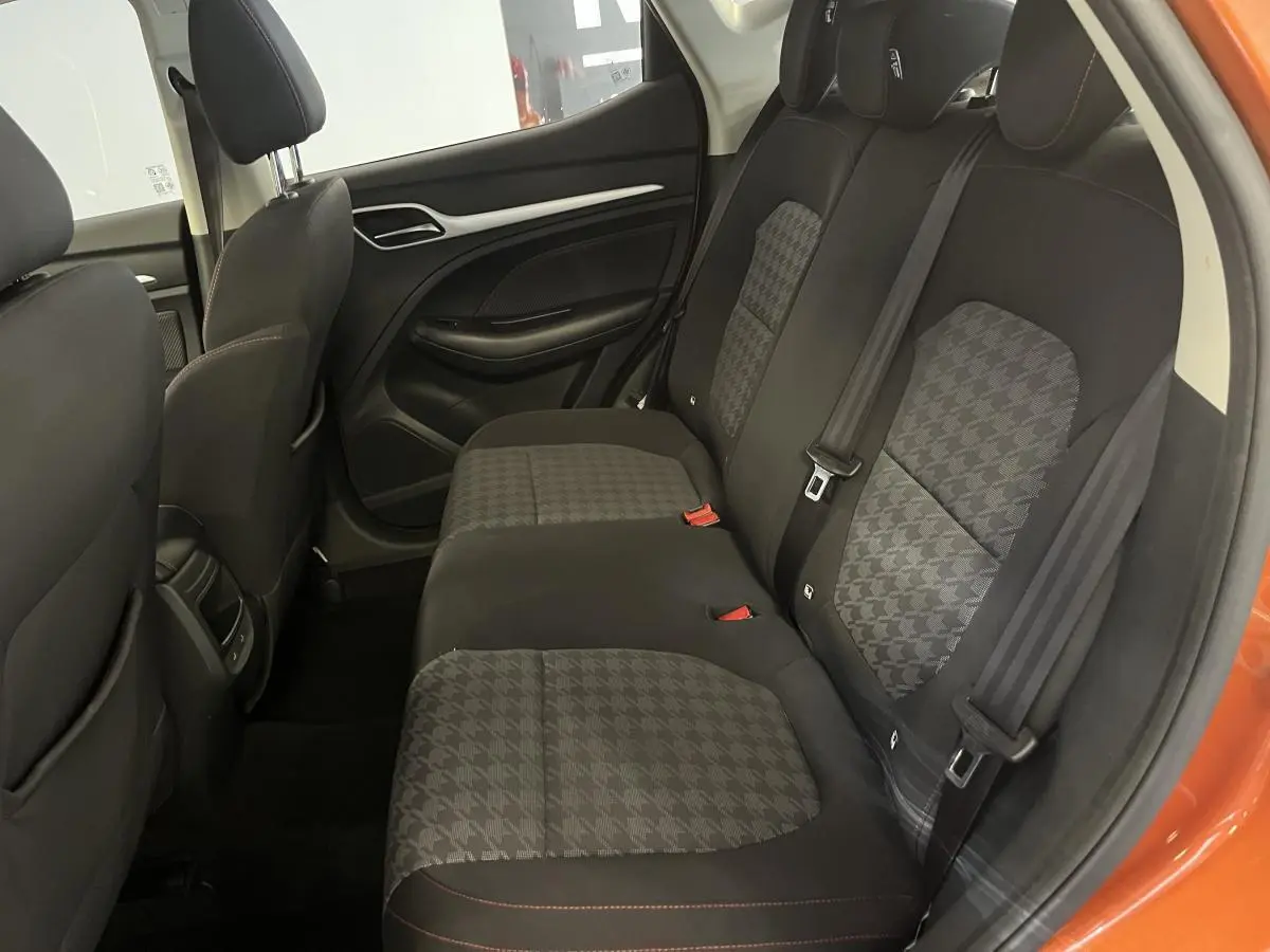 Vue intérieure côté droit sur la banquette arrière en tissu noir et gris du MG ZS orange 2022 avec ceintures de sécurité visibles.