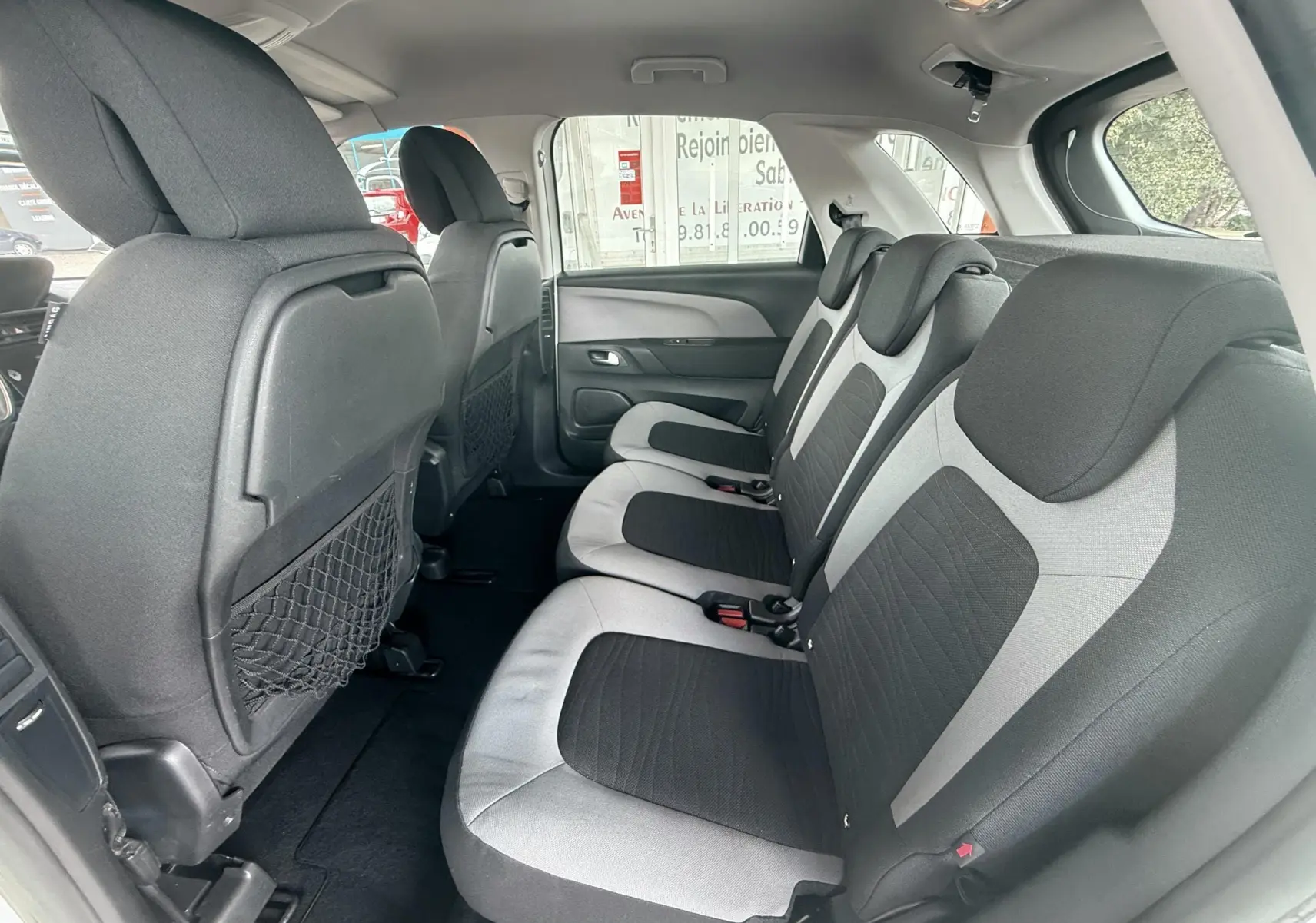 Vue intérieure côté droit des sièges arrière bi-ton gris et noir du Citroën C4 Picasso blanc de 2014.