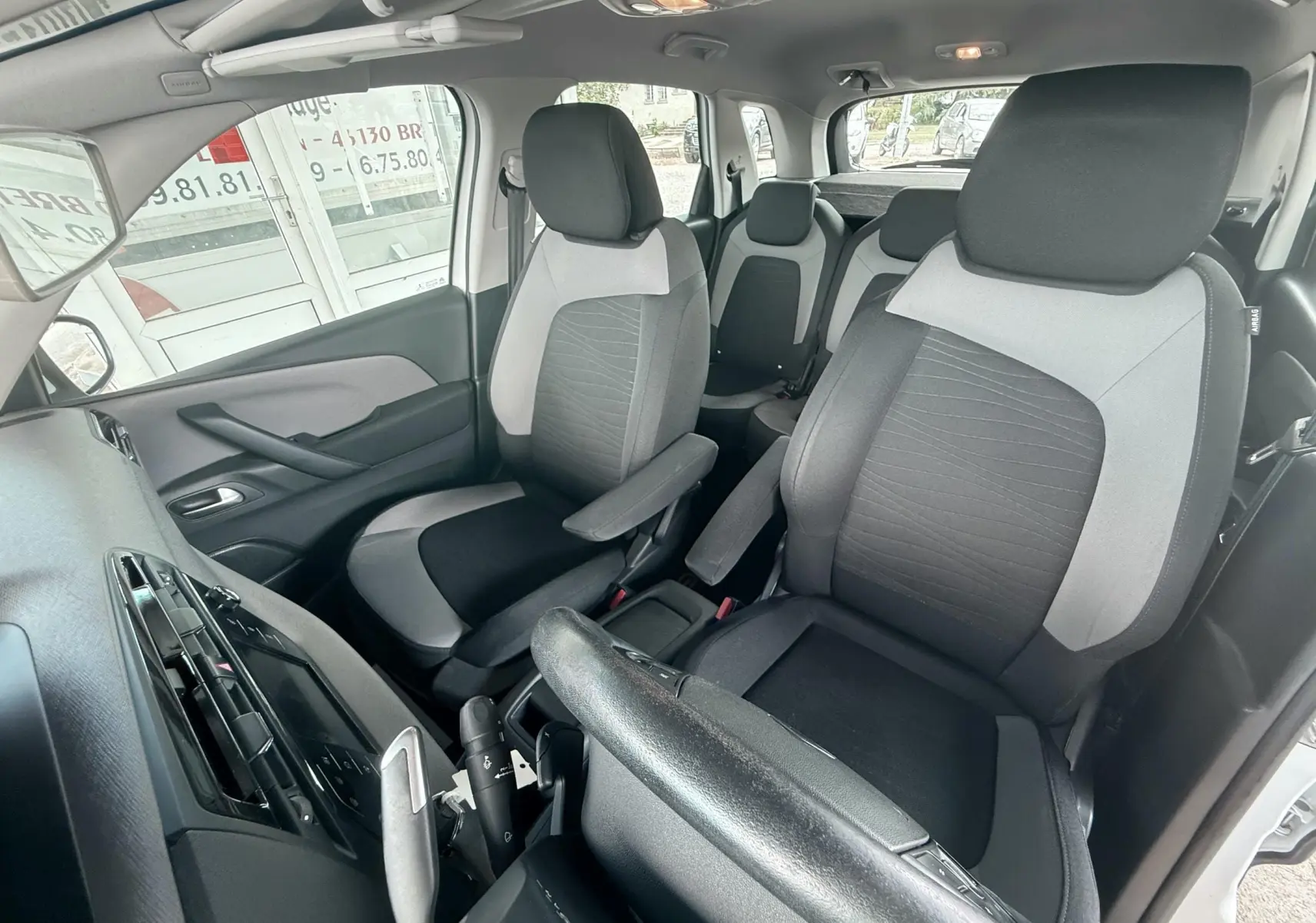 Vue intérieure avant droite du Citroën C4 Picasso 2014, sièges tissu noir et gris, volant et tableau de bord visibles.