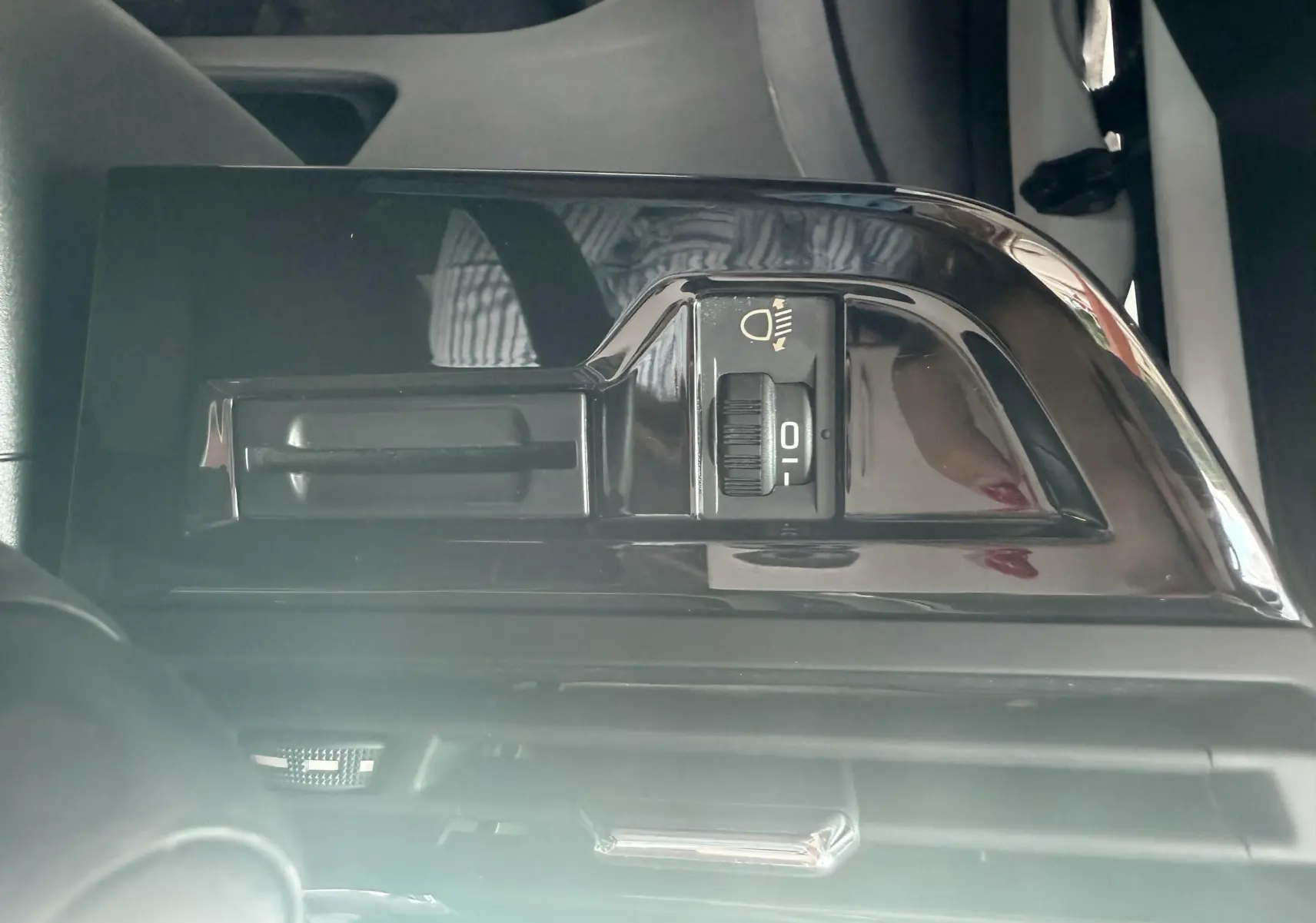 Gros plan sur le réglage de hauteur des phares dans l'habitacle d'une Citroën C4 Picasso blanc de 2014.