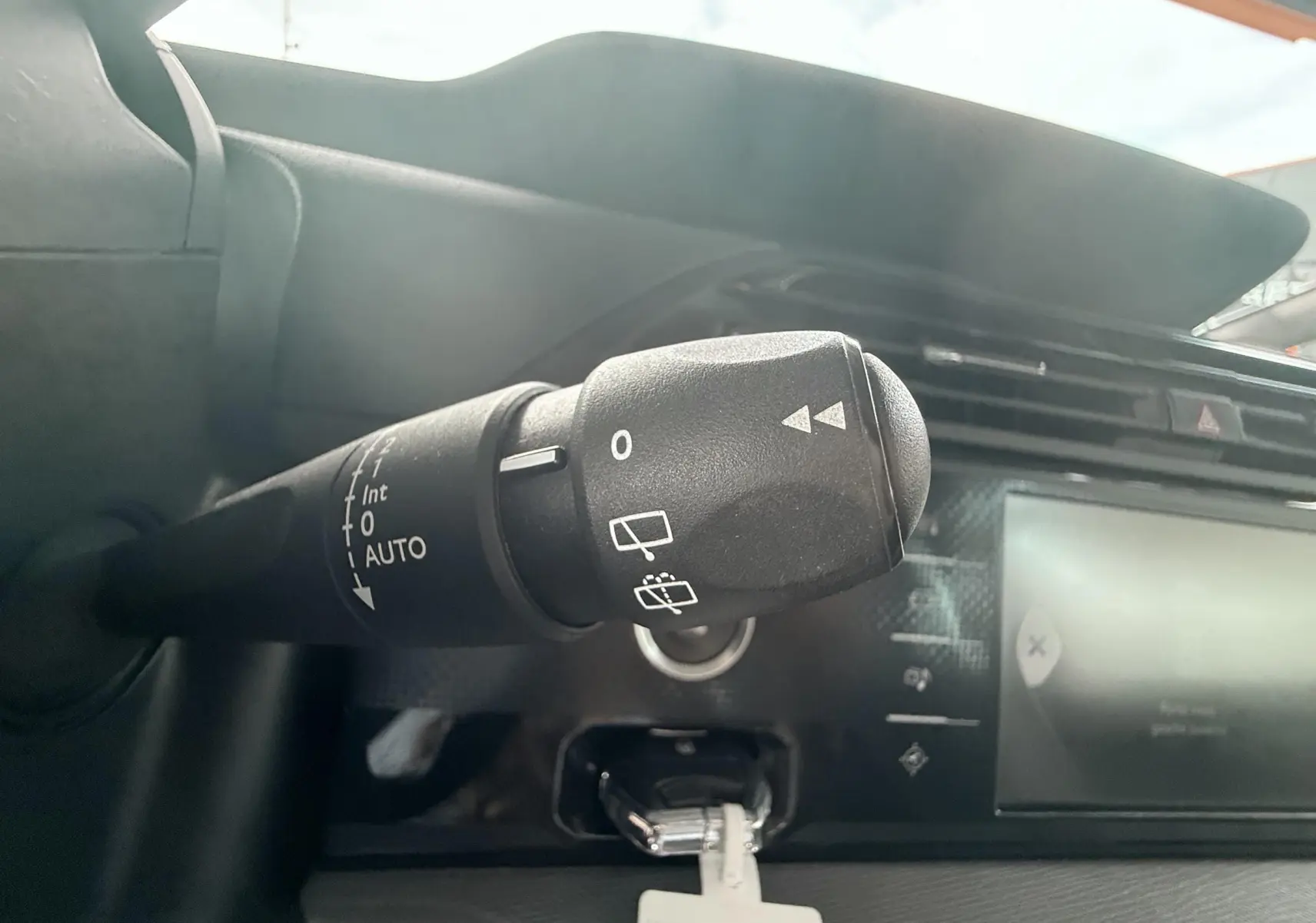 Gros plan sur la commande d’essuie-glace à gauche du tableau de bord du Citroën C4 Picasso blanc de 2014.