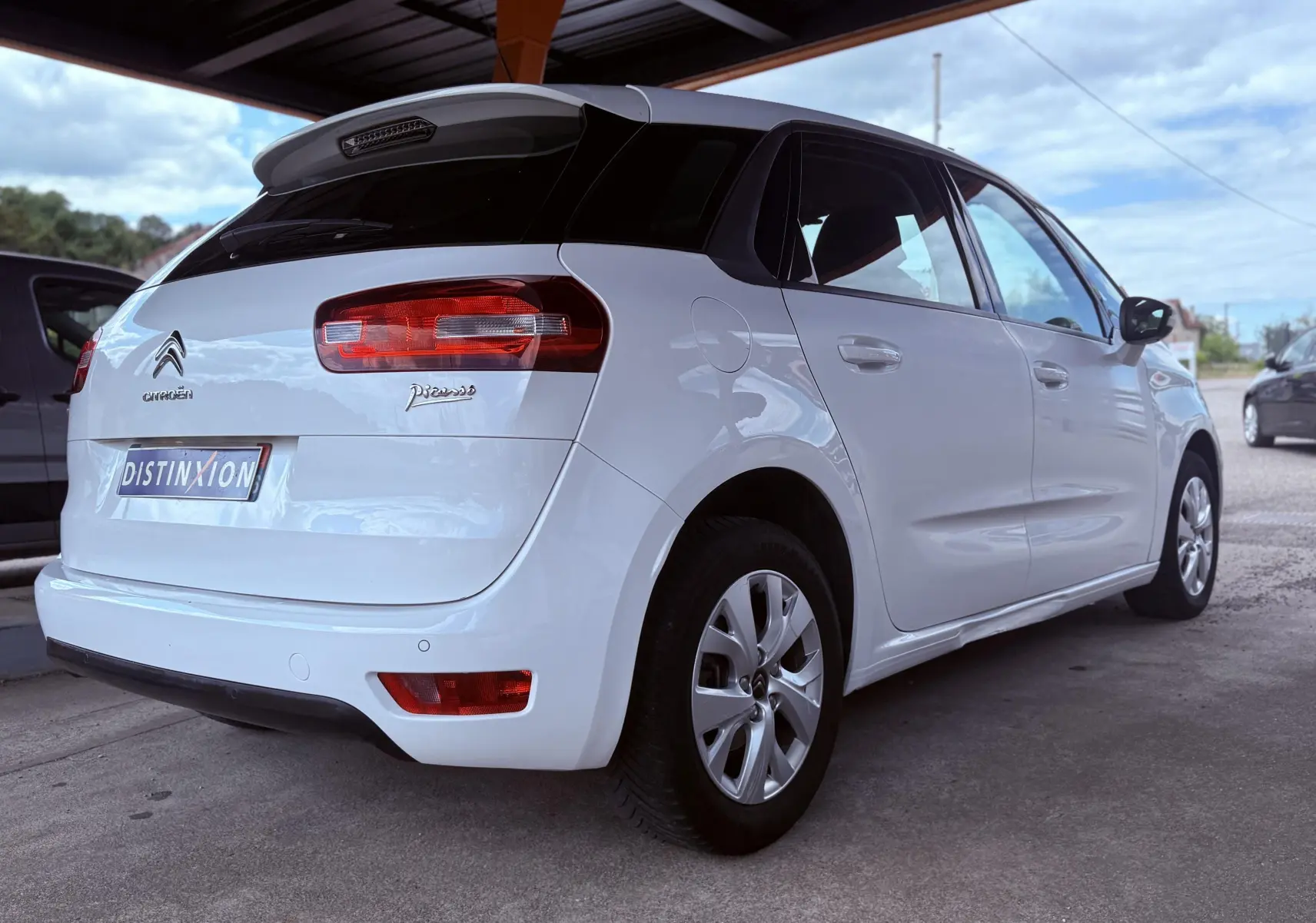 Vue 3/4 arrière droite d'une Citroën C4 Picasso blanche de 2014 avec toit noir et feux arrière rouges.