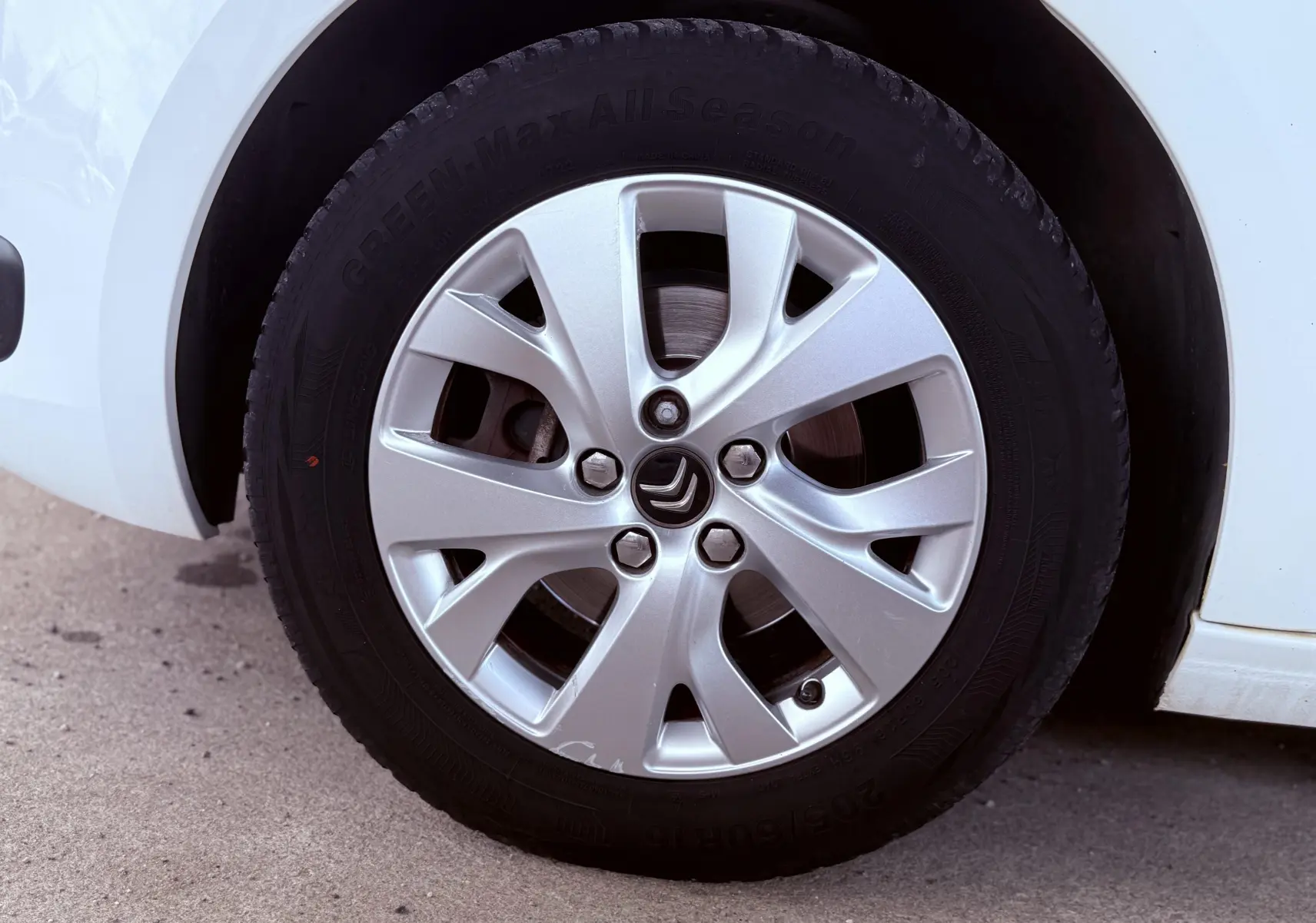 Gros plan sur la roue avant droite blanche d'une Citroën C4 Picasso 2014 avec jante alliage et logo Citroën au centre.