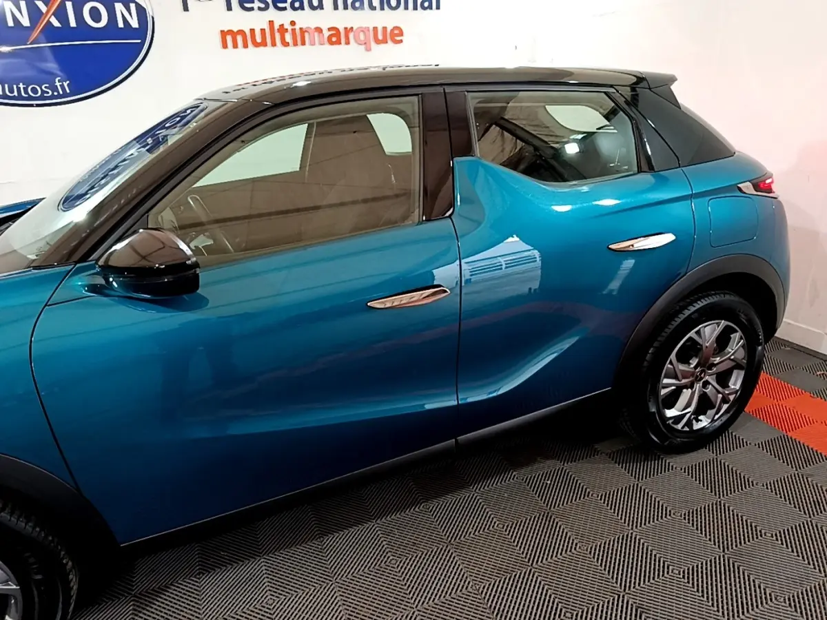 Vue latérale côté gauche du DS3 Crossback bleu avec toit noir et poignées de porte chromées.