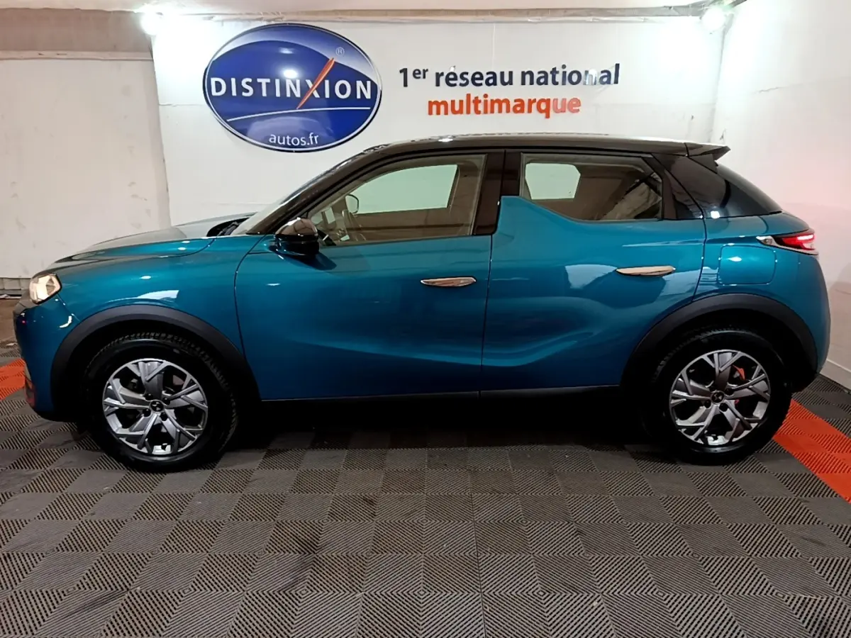 Profil côté gauche d'un DS3 Crossback bleu 2020 dans un showroom avec jantes alliage et toit noir contrasté.