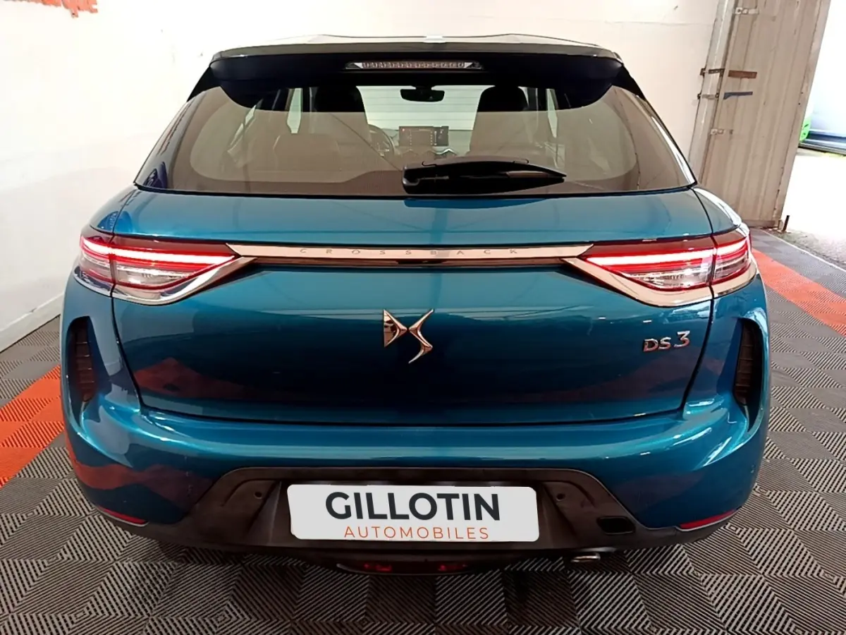Vue arrière d'une DS3 Crossback bleu métallisé avec feux LED et logo DS bien visible sur un sol à damier.