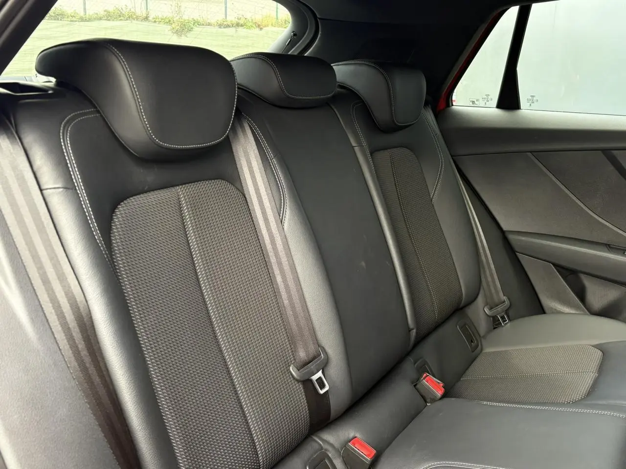 Vue intérieure du siège arrière droit en cuir et tissu noir de l'Audi Q2 35 TDI S-Line rouge 2025.