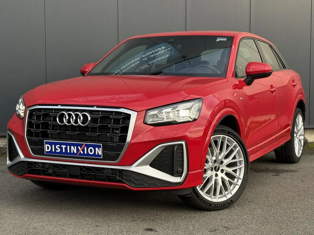 Audi Q2 35 TDI S-Line rouge vue 3/4 avant droit, avec calandre noire et jantes alliage multibranches.
