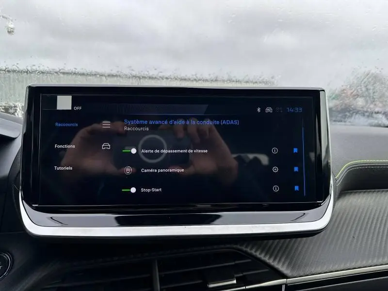Écran tactile central du Peugeot 2008 Hybrid 2025 montrant les options d’aide à la conduite dans un intérieur gris.