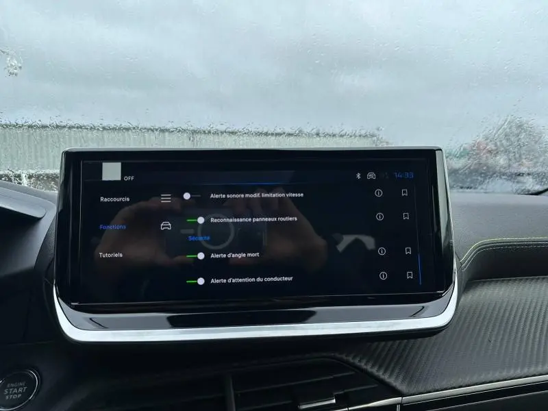 Écran tactile central du tableau de bord du Peugeot 2008 gris 2025, affichant les alertes de sécurité et assistances à la conduite.