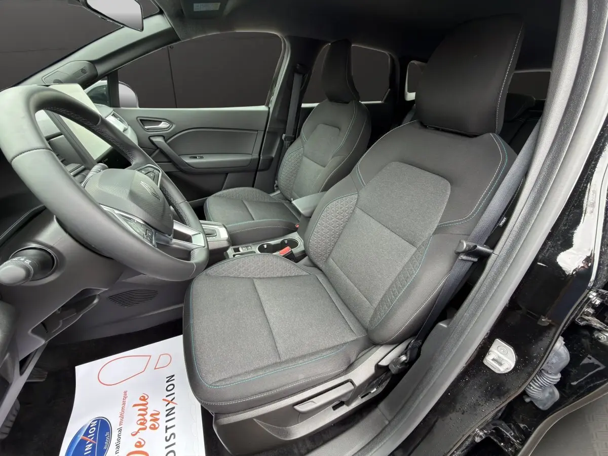 Vue intérieure côté conducteur du Renault Symbioz noir 2025, montrant les sièges avant en tissu gris et le volant multifonctions.