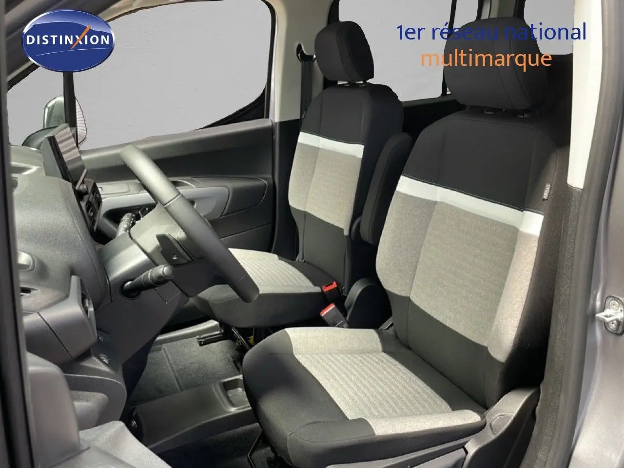 Vue intérieure côté conducteur du Citroën Berlingo gris Artense, sièges tissu bicolore gris et noir, volant multifonction visible.