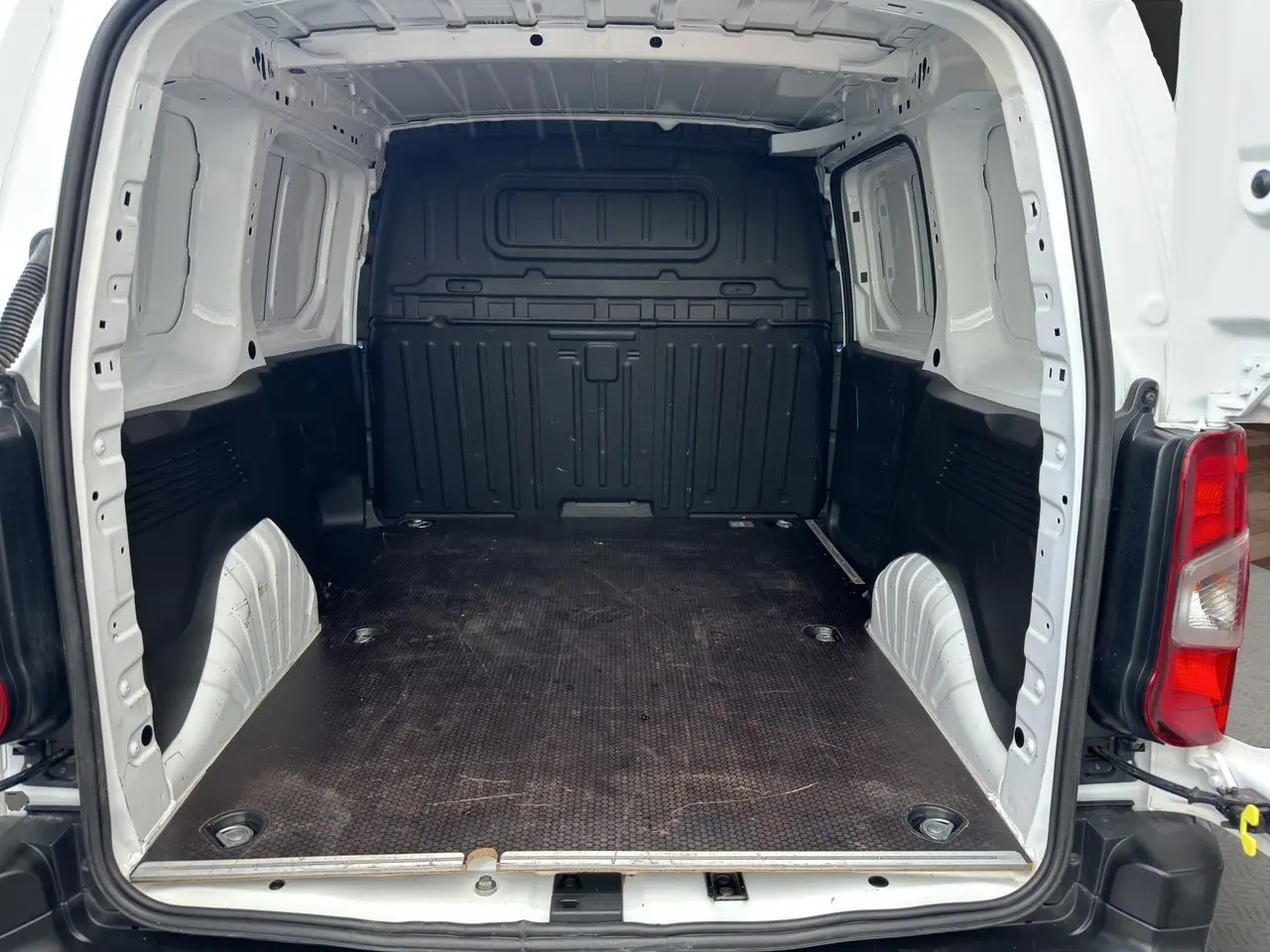 Vue arrière du Peugeot Partner blanc 2022, montrant l'espace de chargement vide avec parois blanches et plancher noir antidérapant.