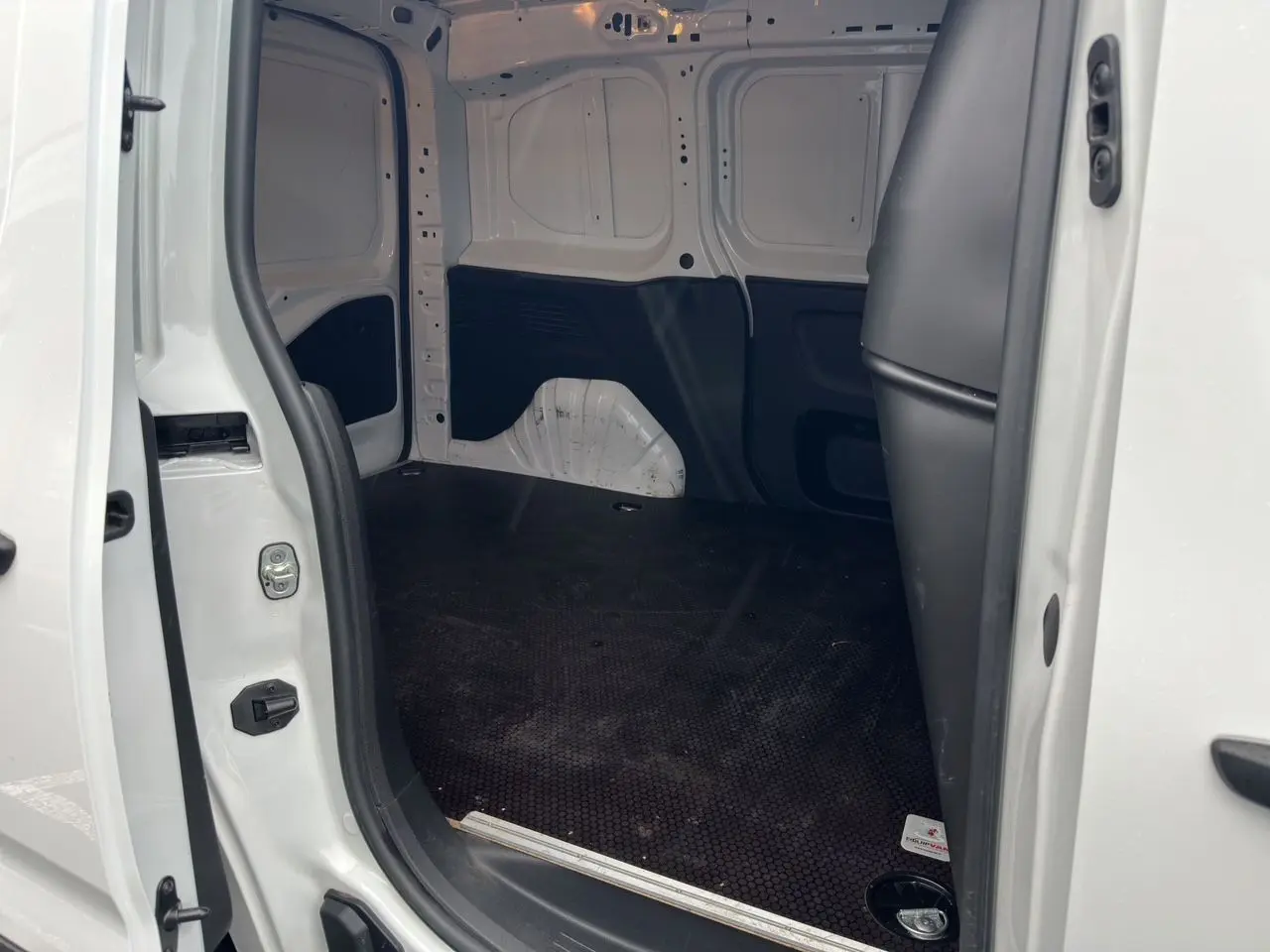 Vue intérieure de la zone de chargement du Peugeot Partner blanc 2022, montrant l'espace vide côté droit avec plancher noir antidérapant.