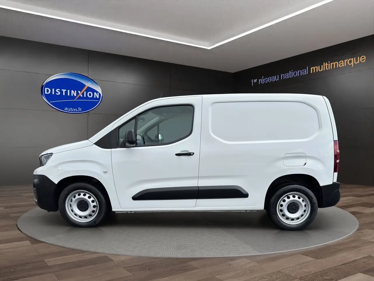 Profil côté gauche d'un utilitaire blanc Peugeot Partner 1000KG BlueHDi 100 Premium, avec protections latérales noires.