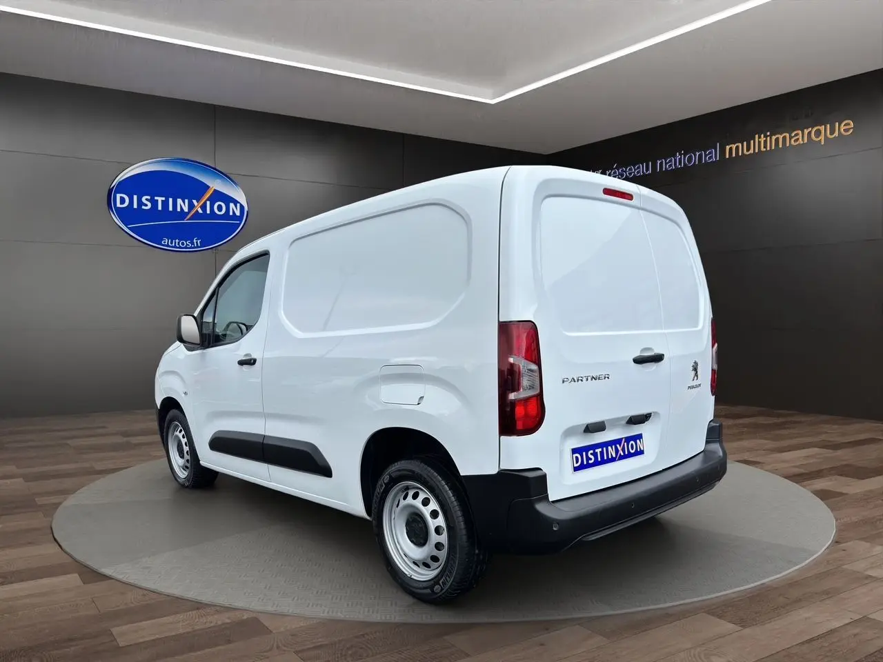 Vue 3/4 arrière droite d'un utilitaire Peugeot Partner blanc 2022 avec logo et plaque Distinxion visibles.