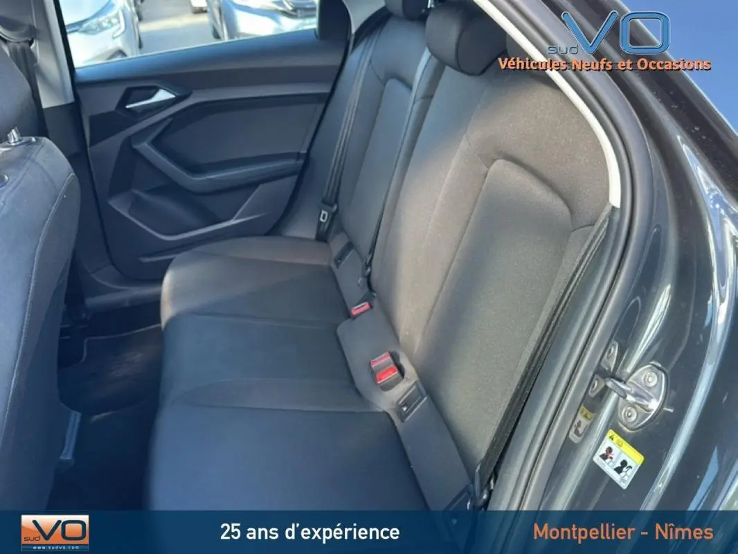 Vue intérieure du siège arrière côté droit de l'Audi A1 Sportback gris foncé avec habillage tissu et ceintures visibles.