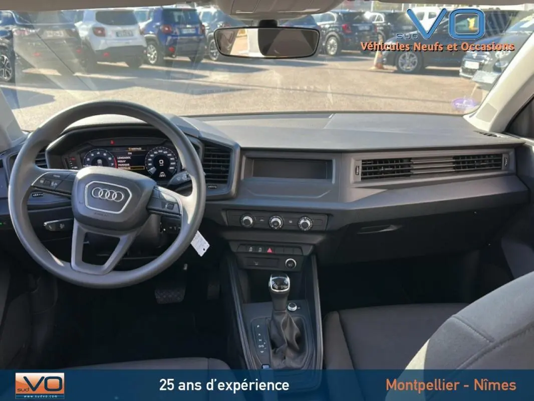 Vue intérieure avant de l'Audi A1 Sportback 30 TFSI 2020 avec tableau de bord gris et console centrale équipée d'une boîte automatique.