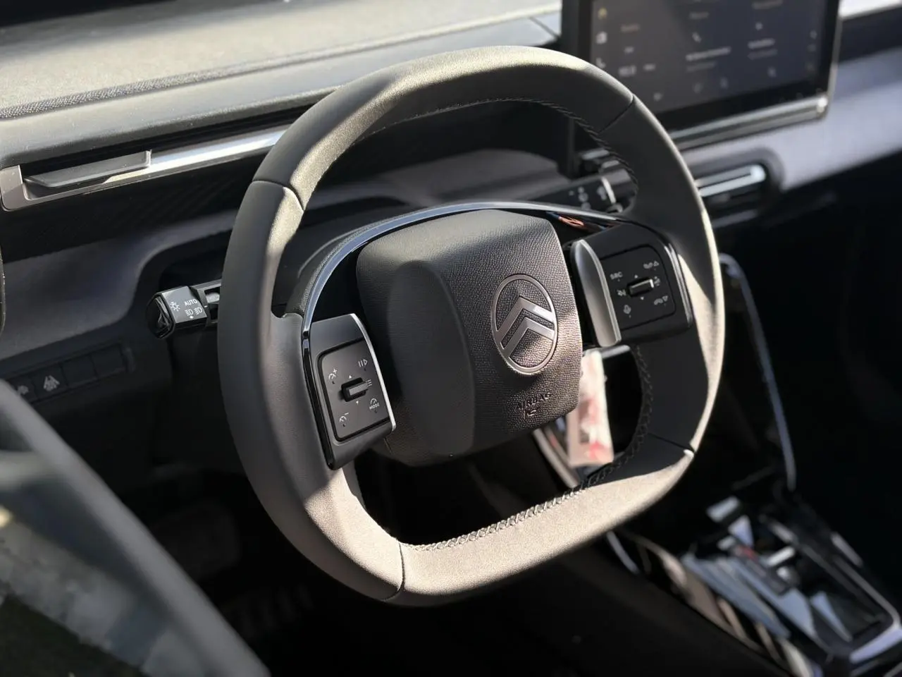 Vue rapprochée du volant multifonctions noir de la Citroën C3 Aircross 2025, avec tableau de bord gris et écran tactile visible.