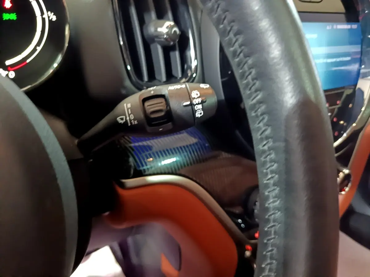 Gros plan sur le volant cuir et la commande d’essuie-glace du MINI Countryman Cooper SE bleu, tableau de bord partiellement visible.