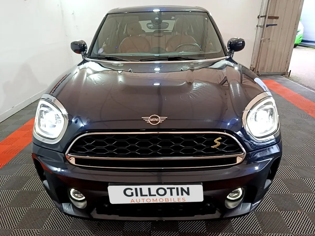 Vue frontale d'une MINI Countryman Cooper SE bleu foncé avec phares allumés et calandre distinctive "S"