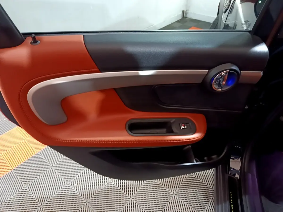 Gros plan sur la porte intérieure côté droit du MINI Countryman 2021, garniture cuir orange et détails argentés.