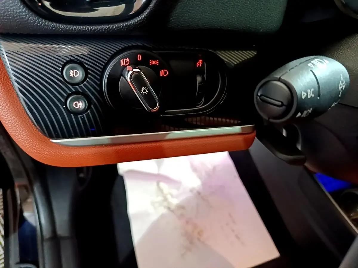 Gros plan sur la commande des phares et la manette multifonction côté gauche du tableau de bord brun et noir de la MINI Countryman.