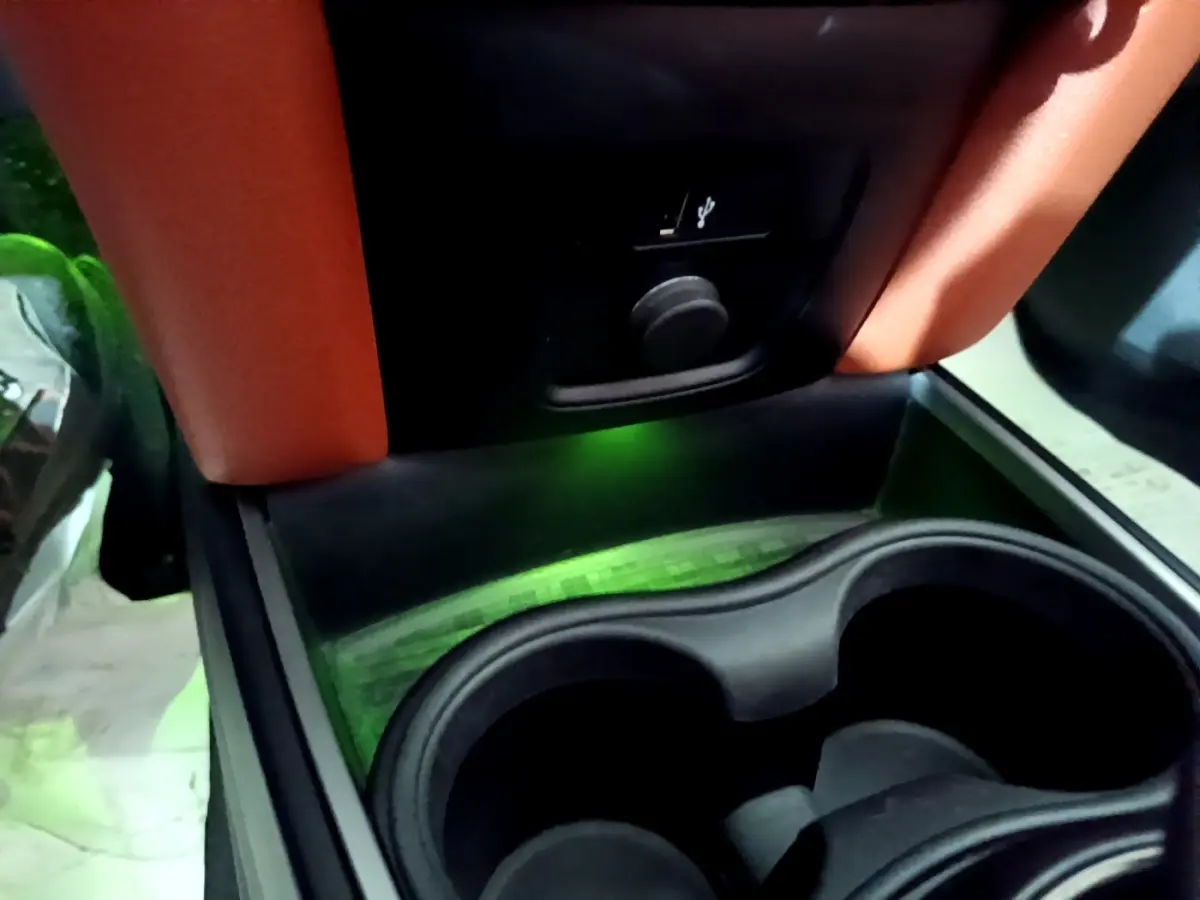 Gros plan sur la console centrale noire avec porte-gobelets et prise USB du MINI Countryman Cooper SE bleu.