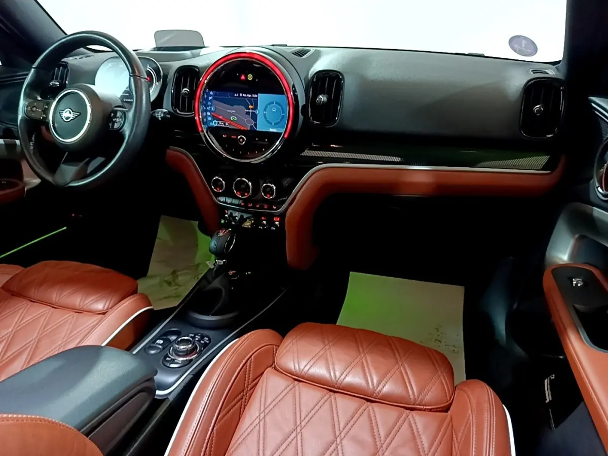 Intérieur avant droit du MINI Countryman Cooper SE avec sièges cuir marron et tableau de bord noir avec écran tactile central.
