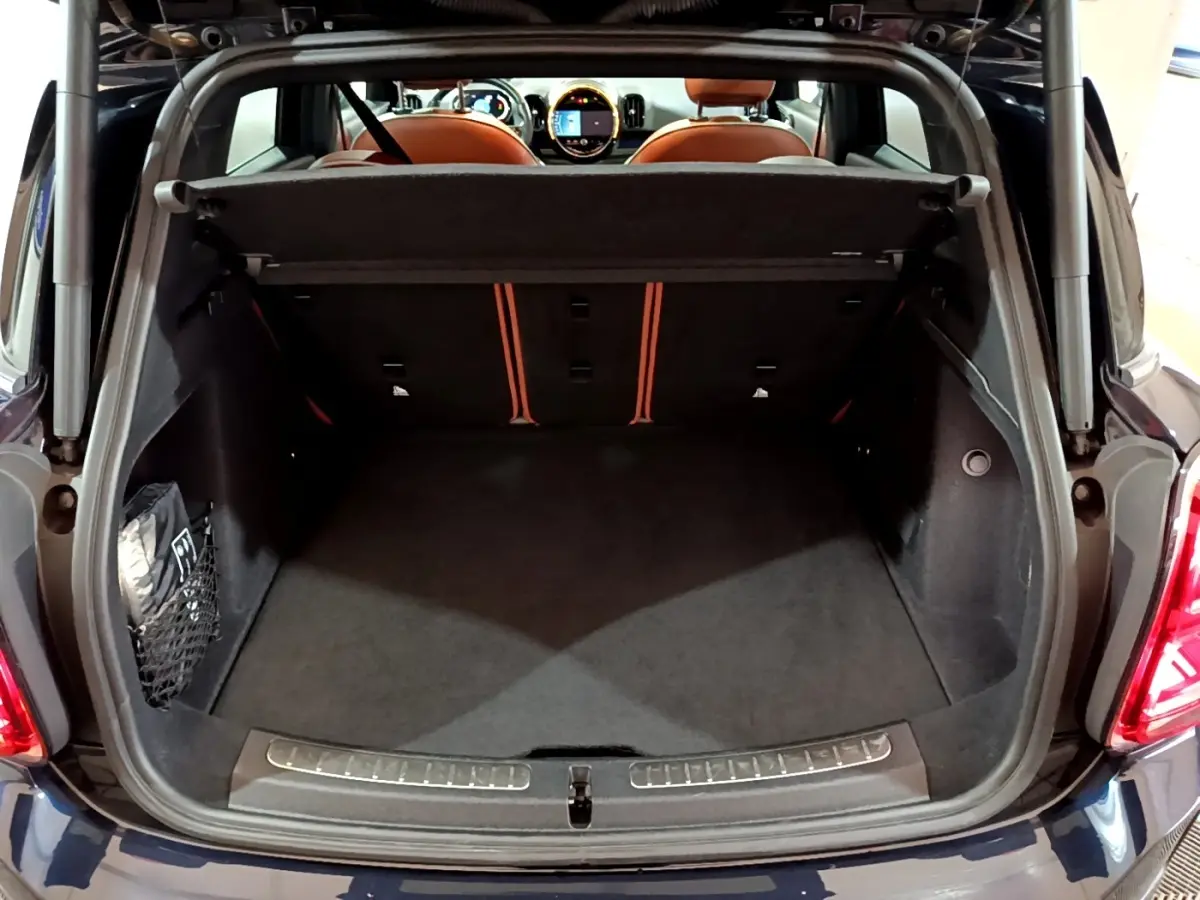 Coffre ouvert vu de l'arrière d'une MINI Countryman Cooper SE bleu, avec banquette arrière et tableau de bord visibles.