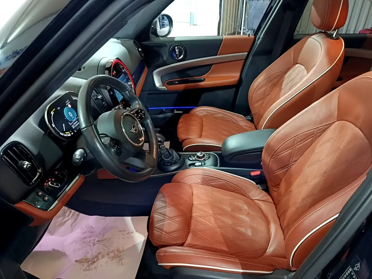Intérieur côté conducteur du MINI Countryman Cooper SE 2021 avec sièges cuir marron et tableau de bord moderne.