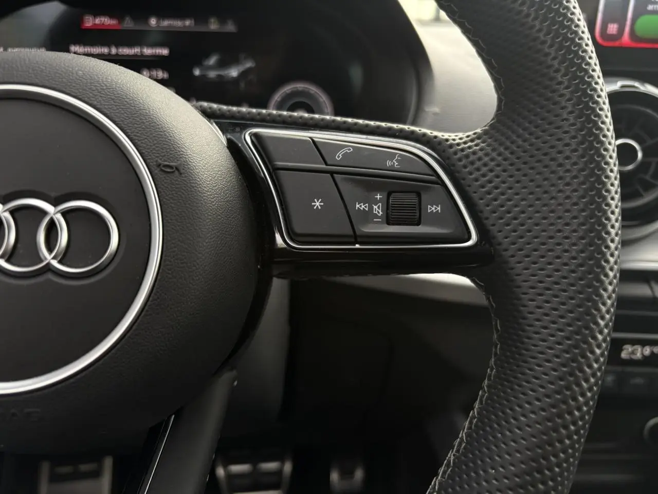 Gros plan sur le volant cuir perforé côté droit de l'Audi Q2 35 TDI 150 S-Tronic S-Line avec commandes multimédia intégrées.