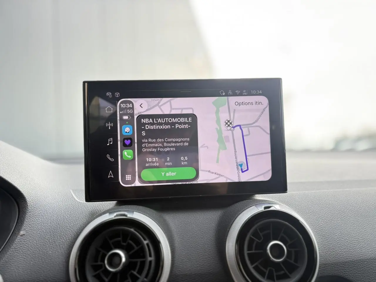 Écran tactile MMI navigation avec carte et itinéraire affichés, intérieur Audi Q2 35 TDI S-Line gris, vue de face rapprochée.